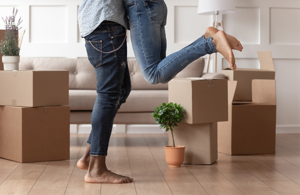 Couple celebrating in their new home surrounded by moving boxes