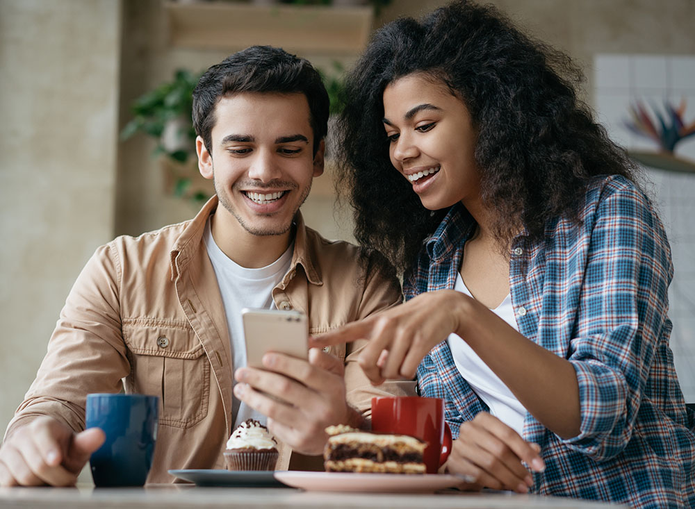 Two people looking at a smartphone together while sitting at a table
