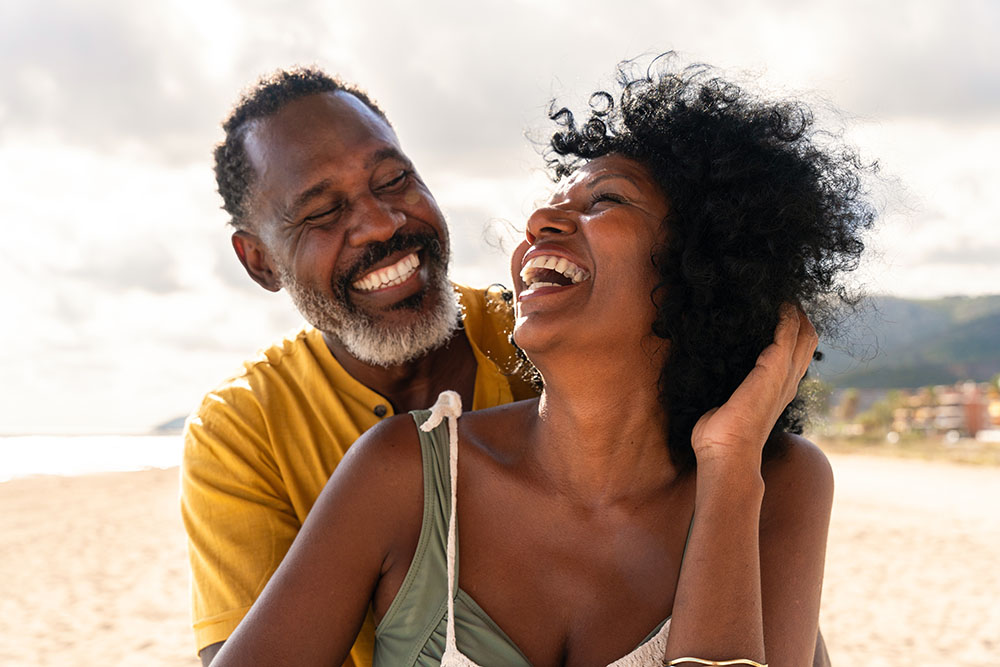 Smiling couple laughing together at the beach
