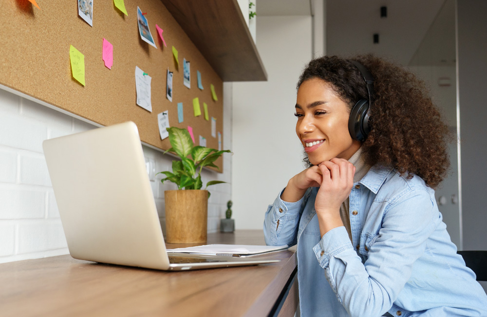 Person with headphones on looking at the laptop and smiling