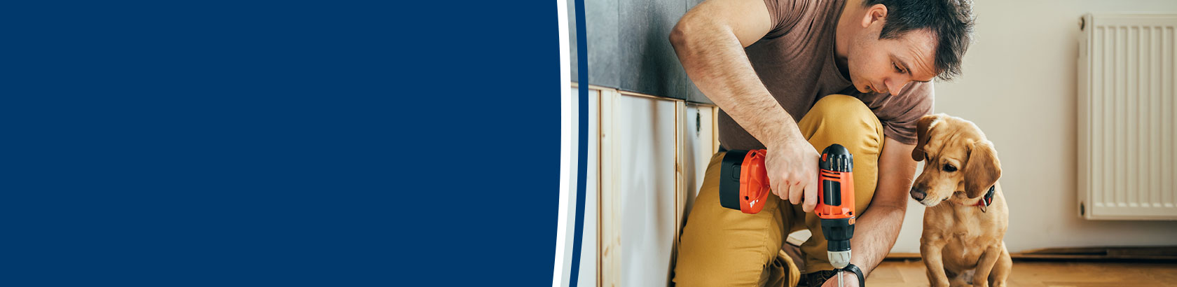 Person using a power drill on a home improvement project while a dog watches nearby