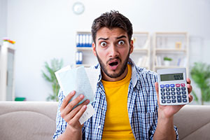 A frustrated man with a calculator and bills
