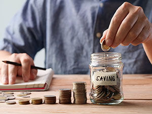 Person putting in a coin into a savings jar