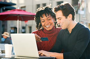 Man and woman in front of a laptop with a debit card