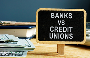 Photo of money and a sign banks vs credit unions.