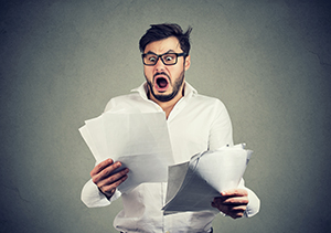 Man with a stack of bills and a shocked look on his face