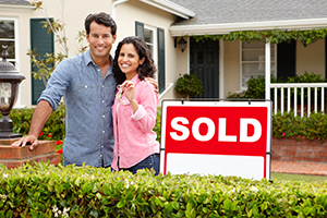 A couple in front of the house with the Sold sign.