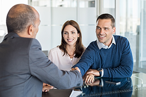 A couple closing on a loan shaking hands with a lender