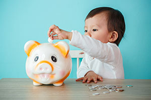 Child depositing money into a savings jar